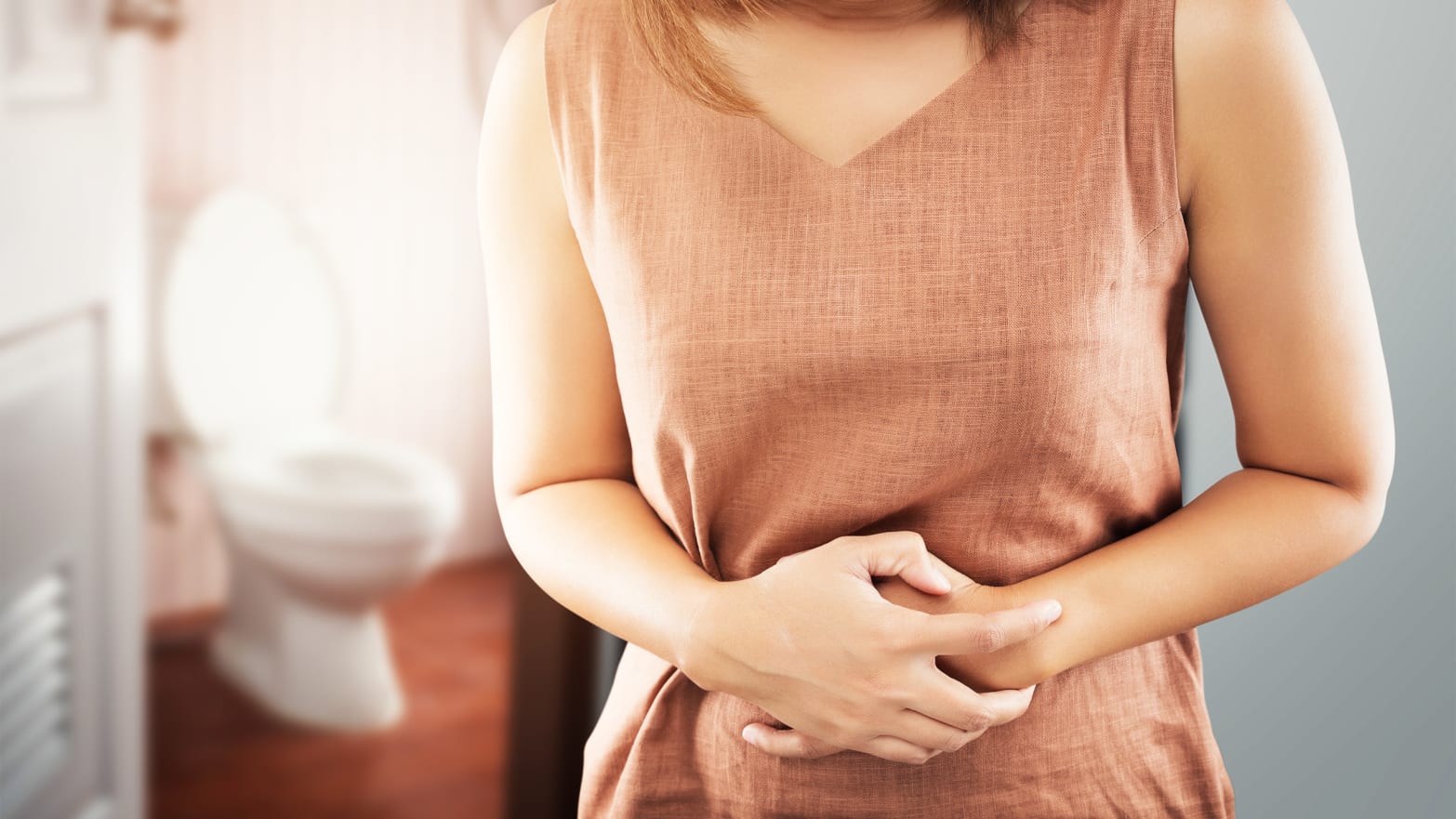 woman clutching stomach in front of toilet american gut project poop crap shit bateria microbiome