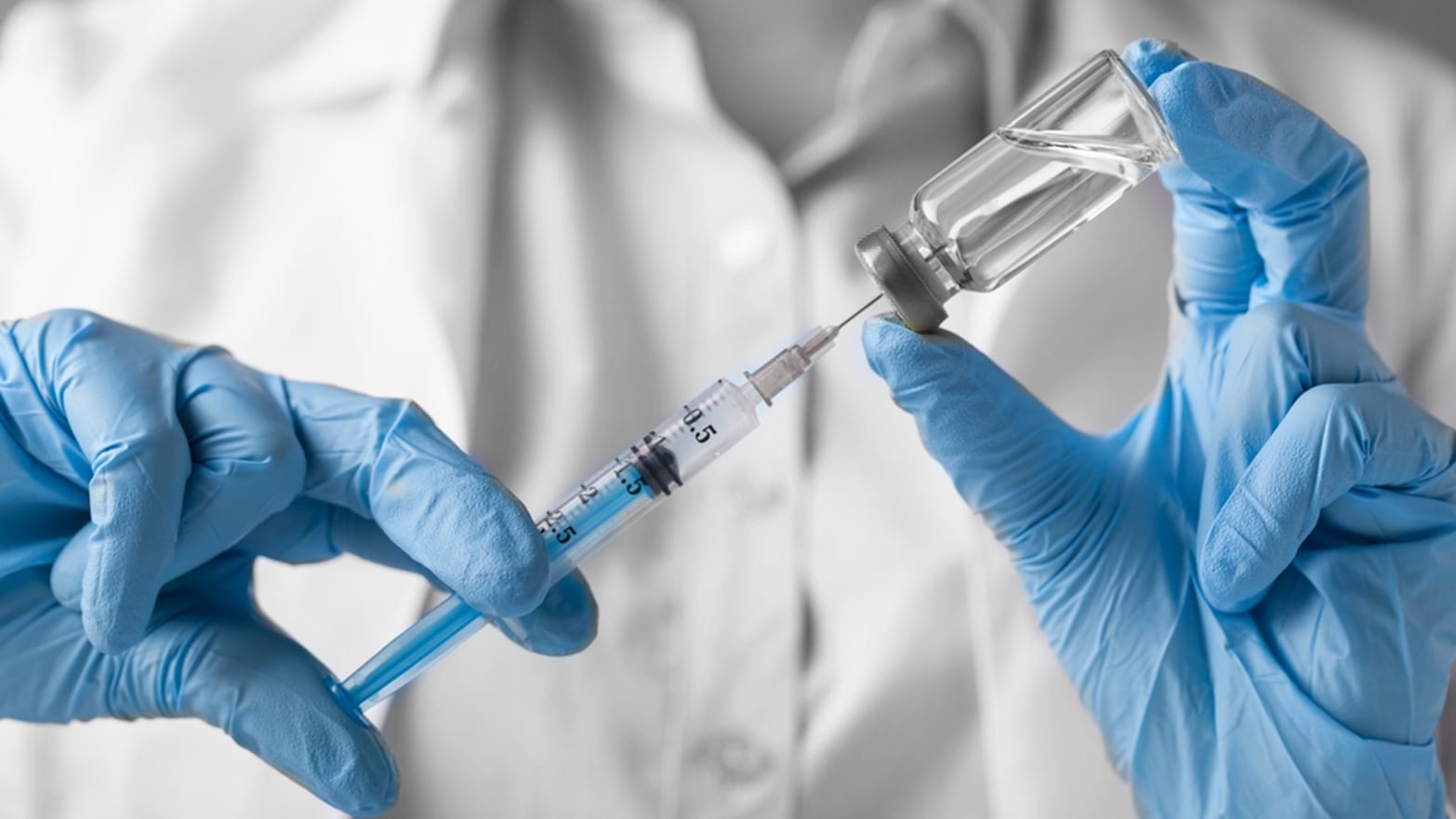 white coat lab technician with blue gloves holding flu shot universal influenza vaccine jab