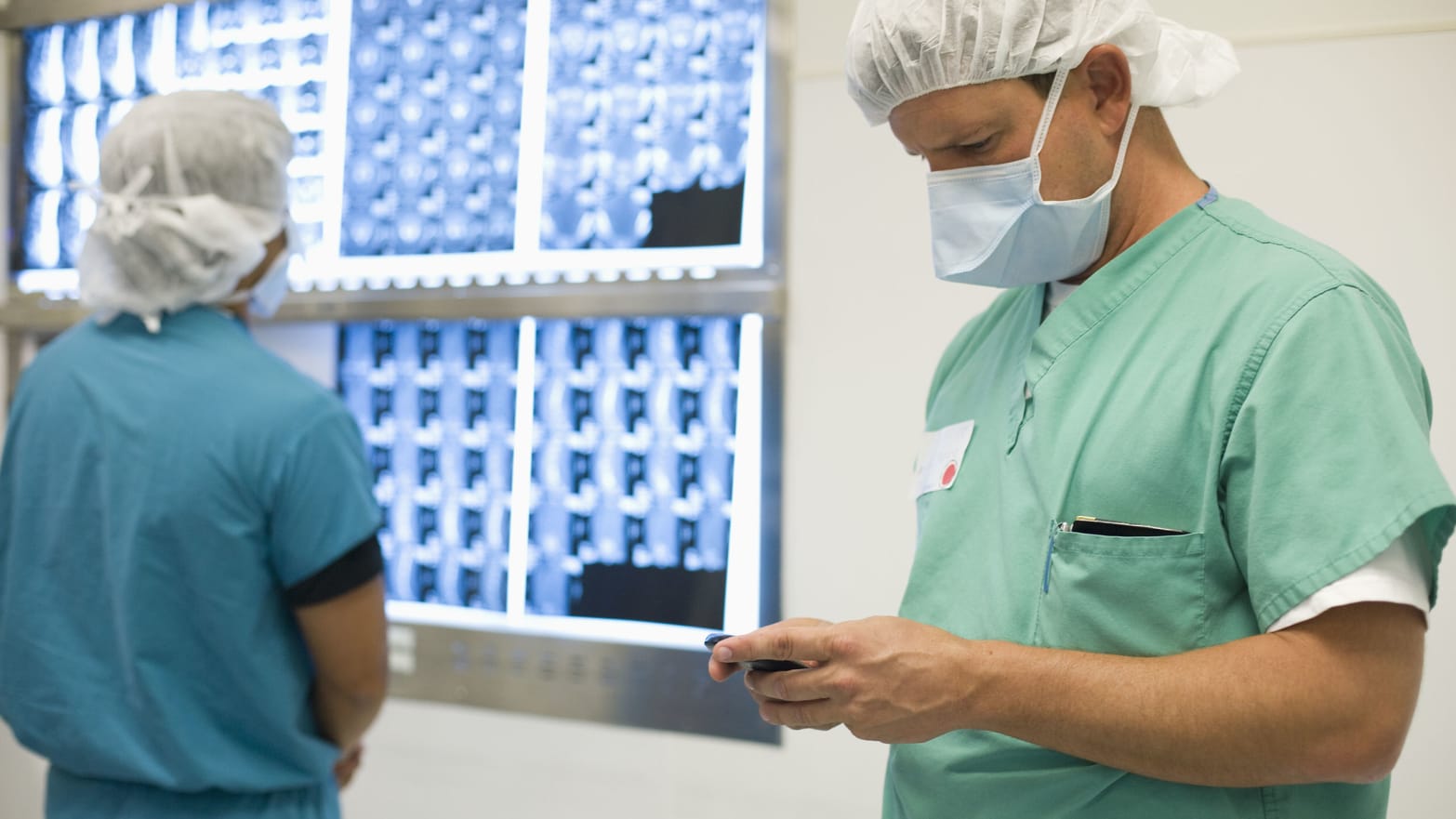 photograph of doctor in scrubs looking at phone while another doctor behind him looks at xrays EASE patrick de la roza Connecticut Children’s Medical Center anxiety nervous surgery