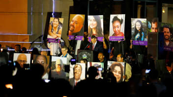 People hold photos of the victims during a moment of silence at a vigil in San Bernardino, California, on Dec. 7, 2015. People gathered to honor the 14 victims shot and killed in a shooting in San Bernardino.