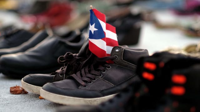shoes holding puerto rico flag death toll maria katrina counting death statistic demography george washington harvard university climate change global warming