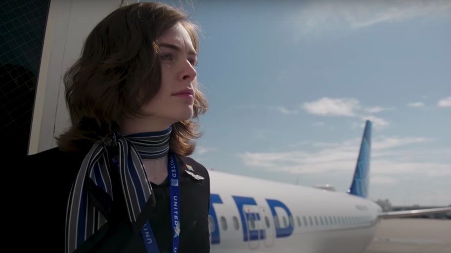 Side view of Kayleigh Scott in a United Airlines uniform in front of a United plane