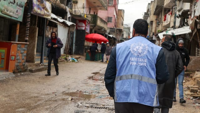A man wearing a jacket bearing the logo of the United Nations Relief and Works Agency for Palestine Refugees
