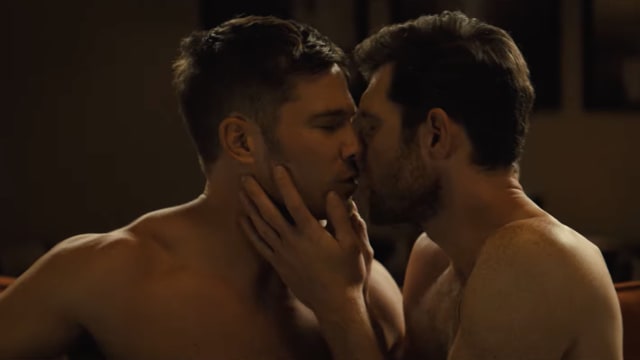 Two men kissing in a hot tub.