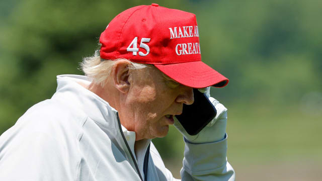 Former U.S. President Donald Trump talks on his phone between shots, as he participates in the Pro-Am tournament ahead of the LIV Golf Invitational at the Trump National Golf Club in Sterling, Virginia, U.S. May 25, 2023.  