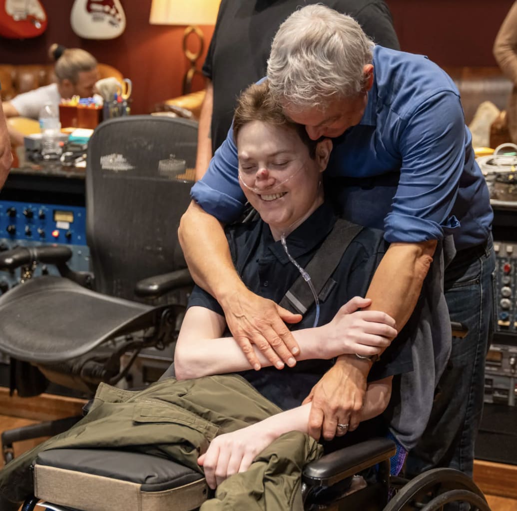 Gary Sinese hugs his son, Mac, in a music studio.