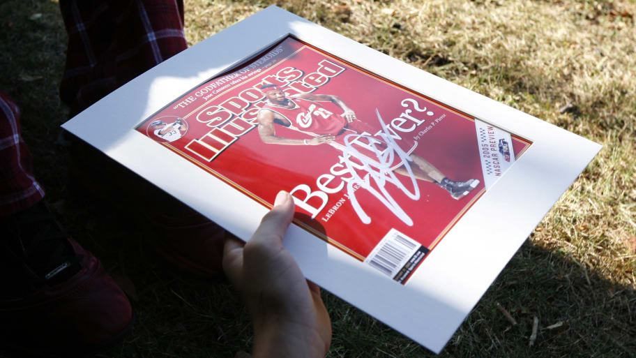 fan holds a framed copy of James on the cover of Sport Illustrated magazine as he waits with others outside the Boys and Girls Club of Greenwich, Connecticut