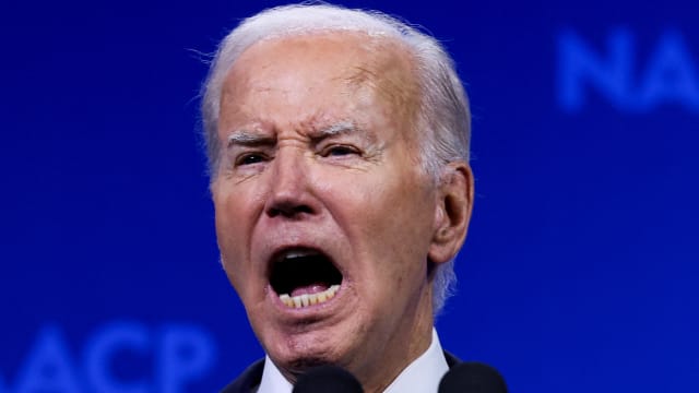 Joe Biden yells while speaking on stage at a conference.