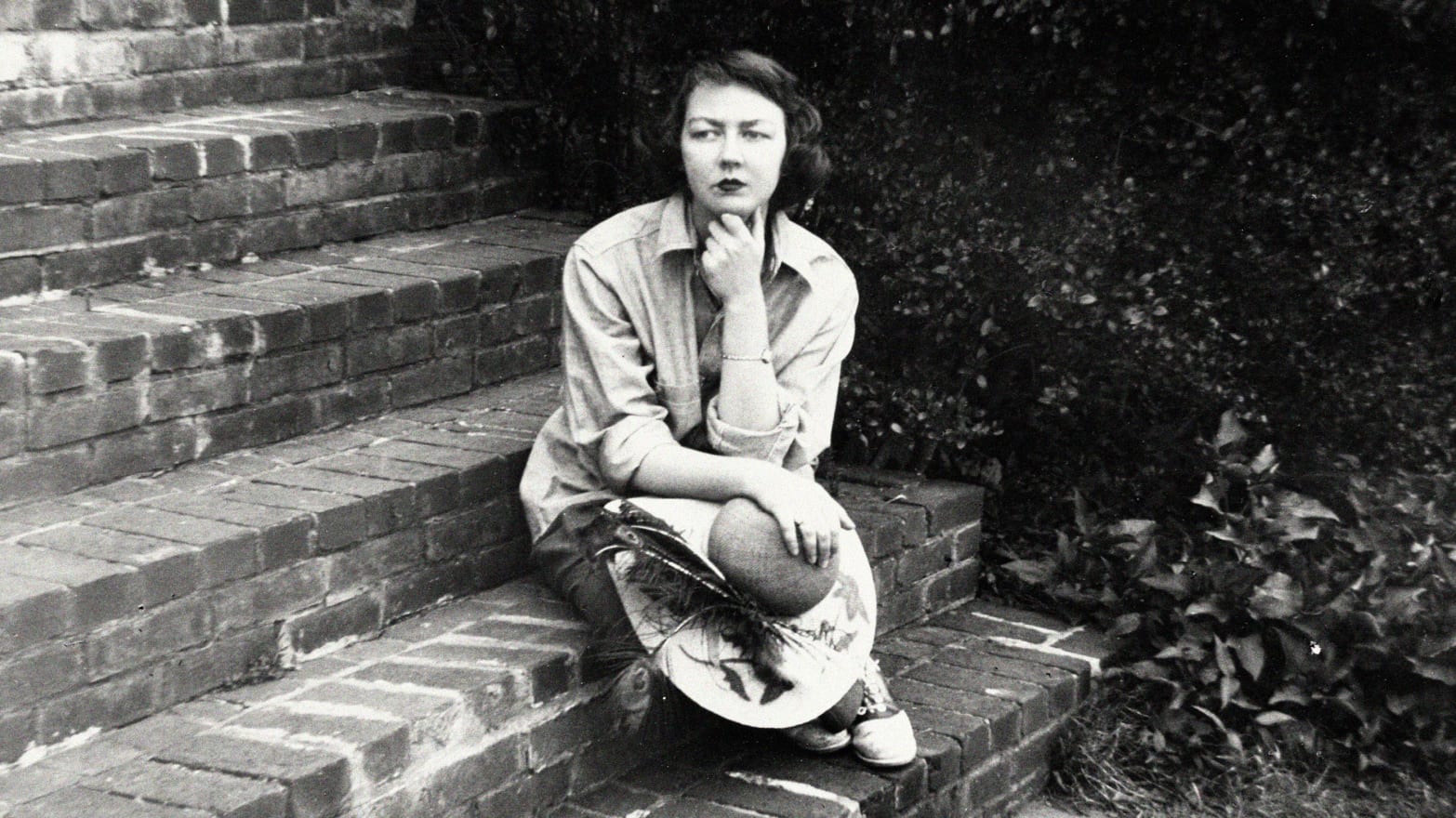 A photograph of Flannery O'Connor sitting on the steps of her home in Milledgeville, Ga. on Sept. 22, 1959.