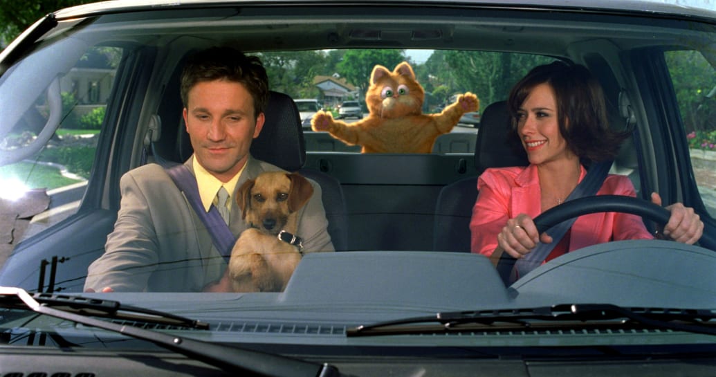 Breckin Meyer and Jennifer Love Hewitt sit in a car with Garfield splattered against the window in a still from ‘Garfield: The Movie’