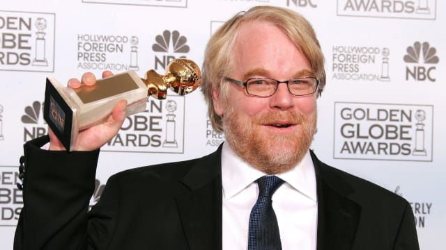 Philip Seymour Hoffman posing on the red carpet with his Golden Globe award.