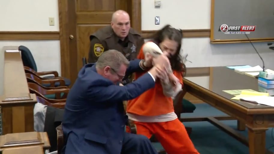 Taylor Schabusiness attacks her attorney in court while a baliff rushes to intervene. 