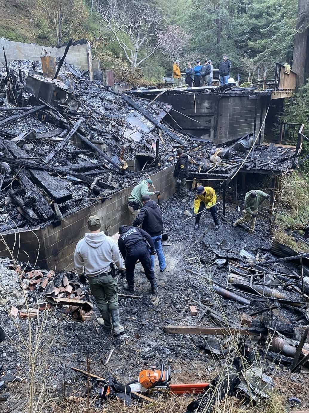 Authorities search the rubble of a burned home.