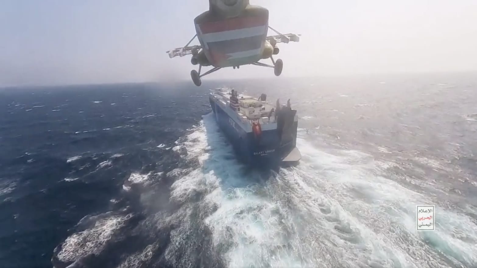 A helicopter descending toward a cargo ship at sea.
