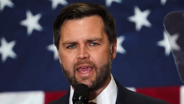 JD Vance speaks in front of an American flag.