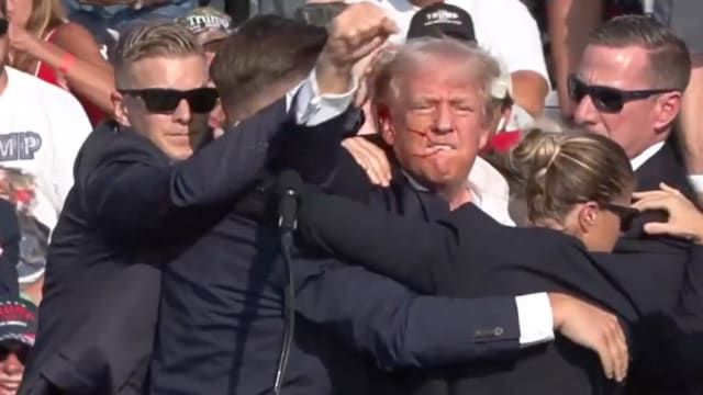 An injured Donald Trump waving his fist at his rally,