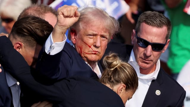 Donald Trump at a rally with blood on his face.