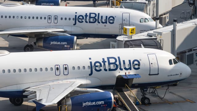 Two JetBlue planes parked at an airport.