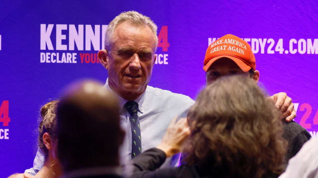 A photo of RFK Jr. with his arm around a person wearing a MAGA hat.