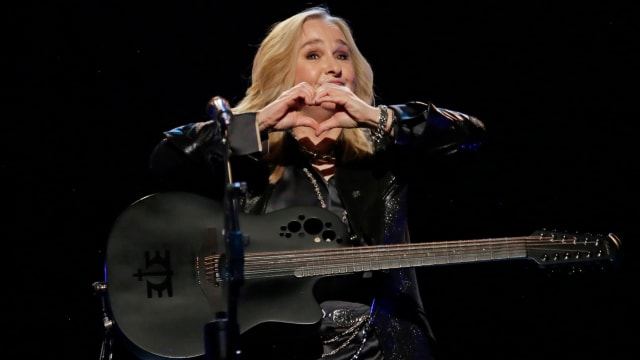 A photo of Melissa Etheridge performing and making a heart