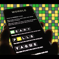A photo illustration of a person holding a phone playing Wordle.