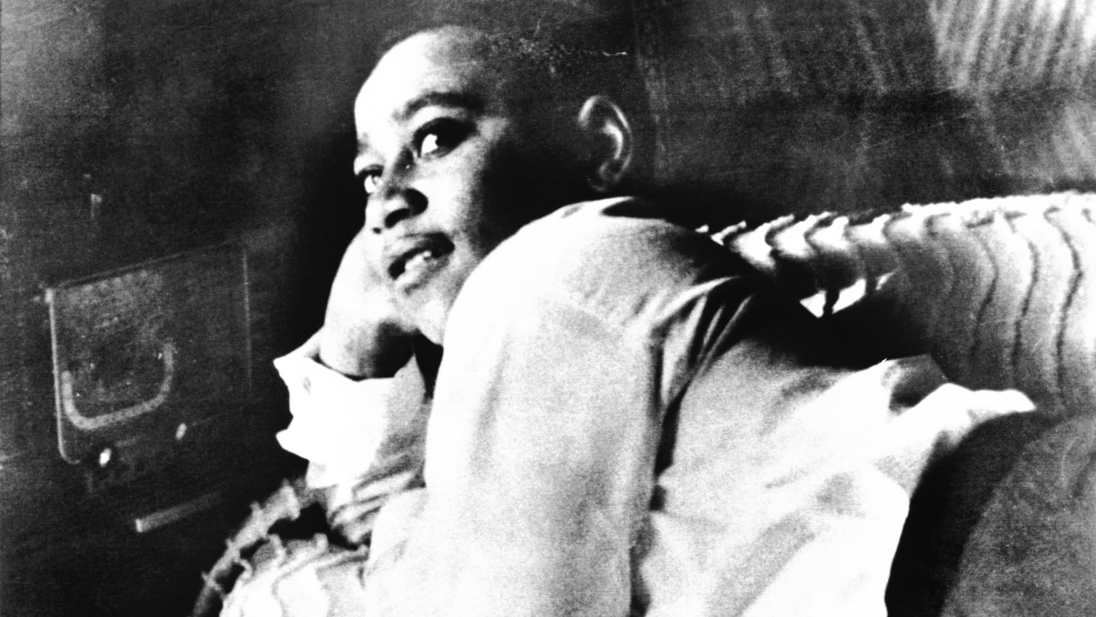A photo including Emmett Till is shown lying on his bed.
