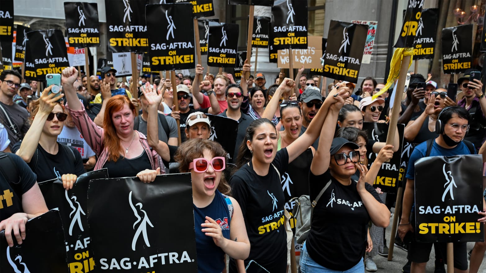 Members of the Writers Guild of America East and SAG-AFTRA cheer and react as they walk the picket line outside Netflix.