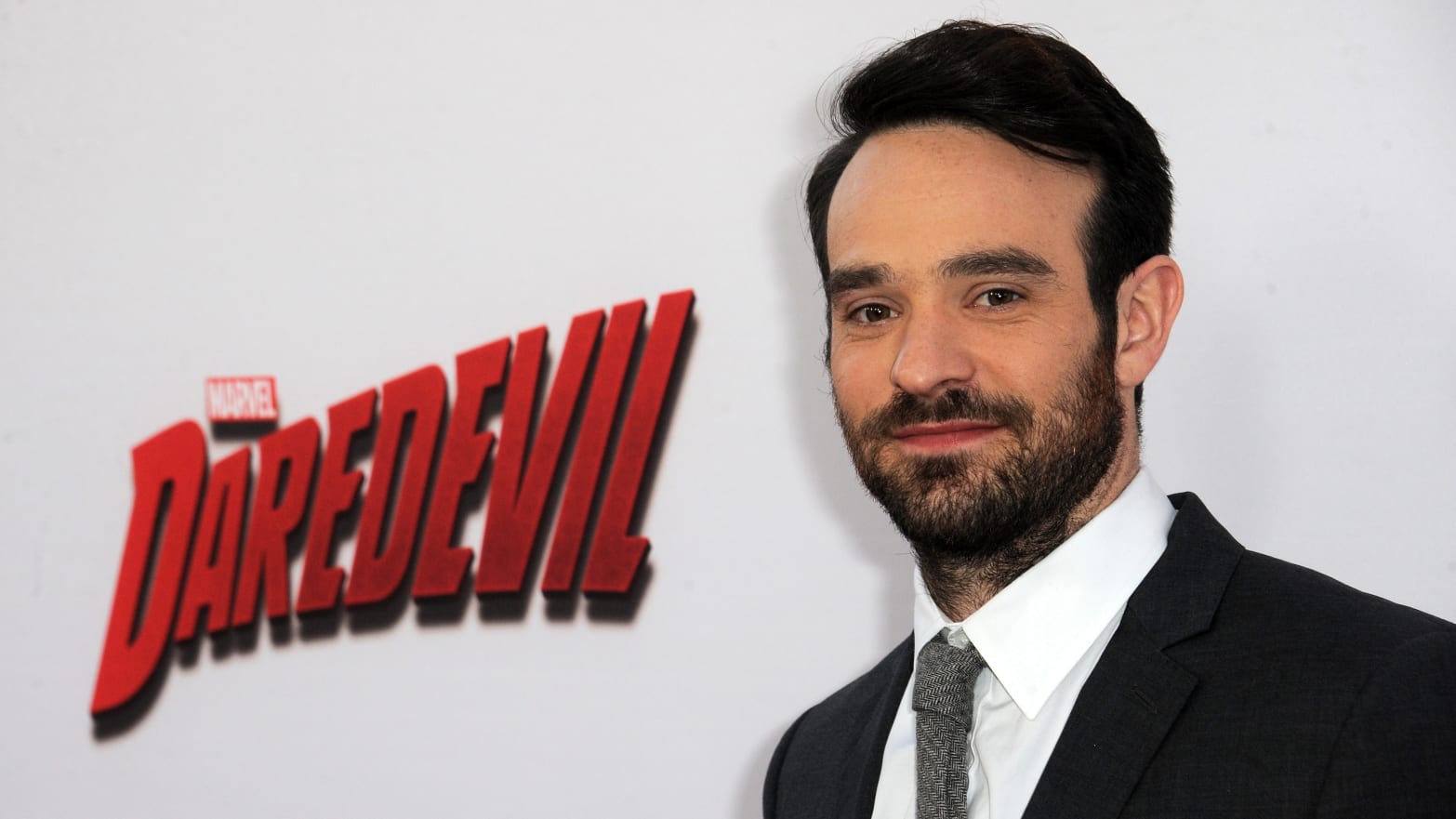 Charlie Cox stands in front of a "Daredevil" backdrop at a premiere event