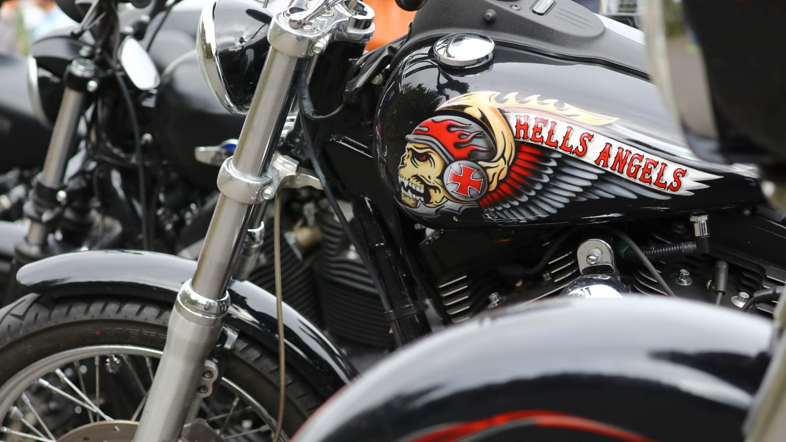 A parked Harley-Davidson motorcycle with a Hells Angels logo and a fierce-looking skull painted on the gas tank.