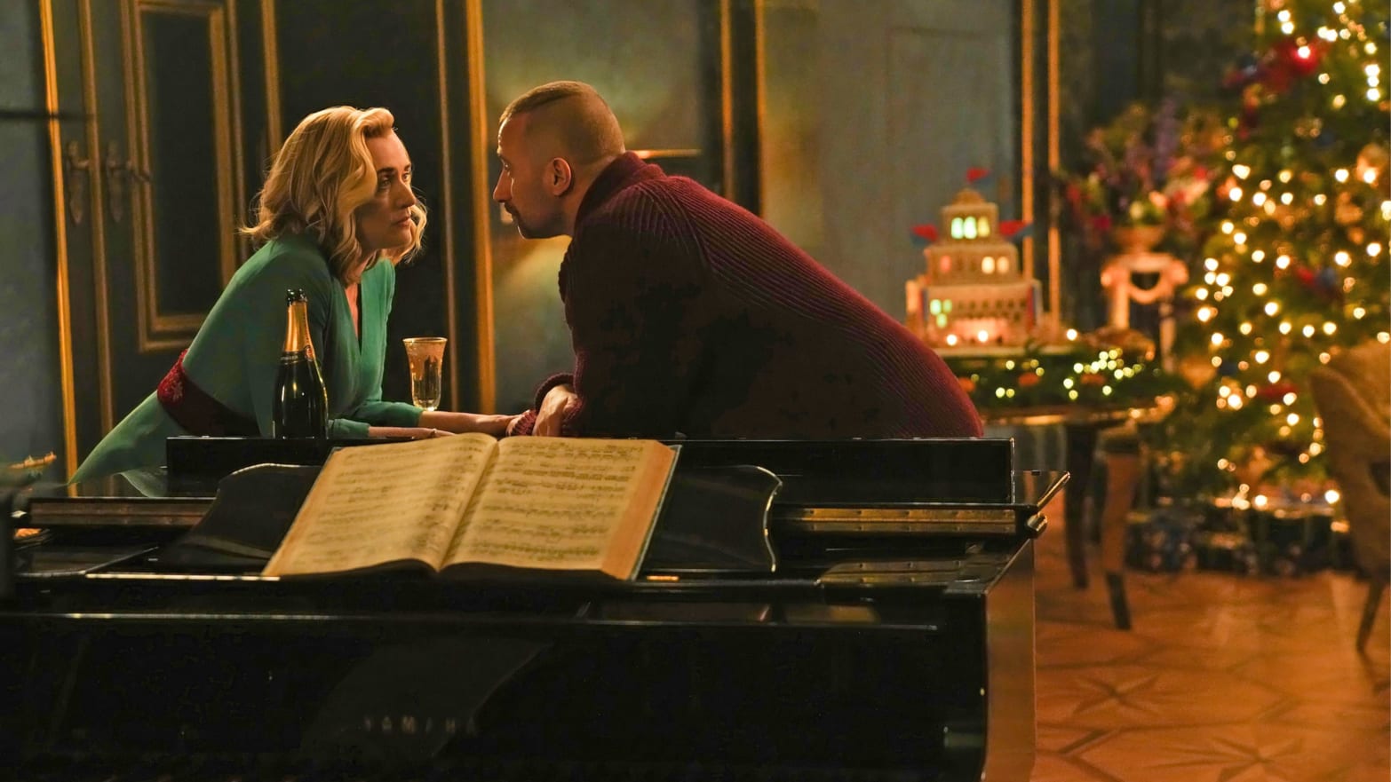 Kate Winslet and Matthias Schoenaerts lean on a piano in a still from 'The Regime'