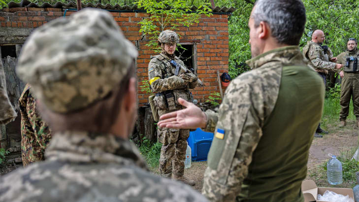 Three Ukrainian soldiers talk outside in Zolochiv 