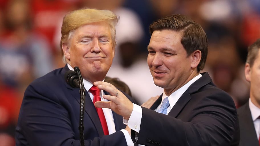 Donald Trump and Ron DeSantis stand in front of a podium.