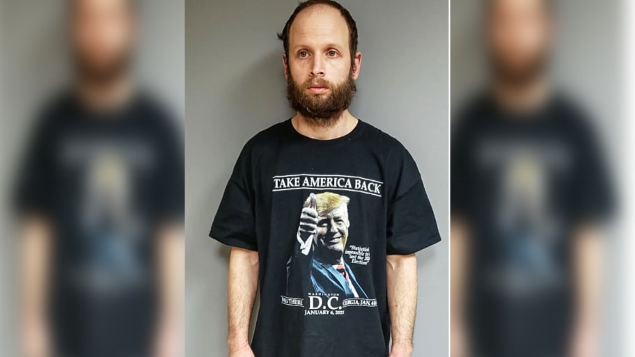 Garret Miller's mugshot showing him in a Trump shirt that says “I was there, Washington, D.C., January 6, 2021”