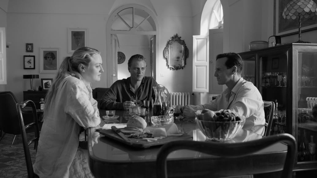 Dakota Fanning, Johnny Flynn and Andrew Scott sit at a table in a still from 'Ripley'