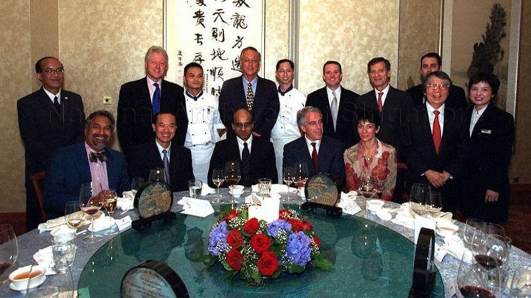 Photo shows a group of people posing behind a dinner table including Goh Chok, Bill Clinton, Ghislaine Maxwell and Jeffrey Epstein 