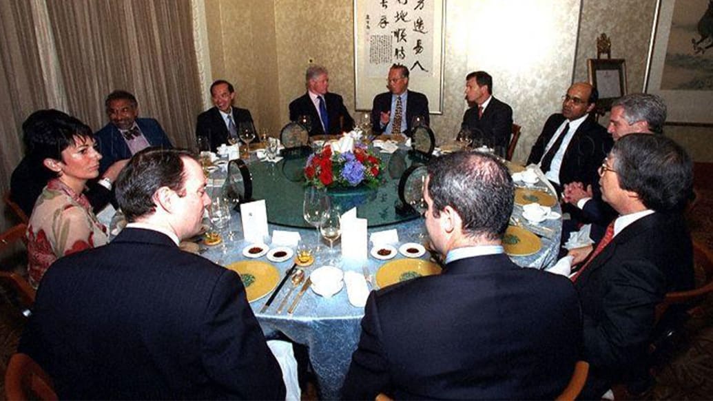 The photo shows a group of people around a dinner table, including Goh Chok, Bill Clinton, Ghislaine Maxwell and Jeffrey Epstein. 