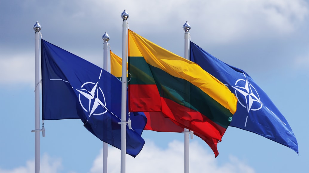 A photo of the NATO and Lithuanian flags flying in Vilnius, Lithuania.