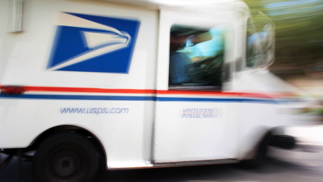 A photo including a U.S. Postal Service Mail Carrier