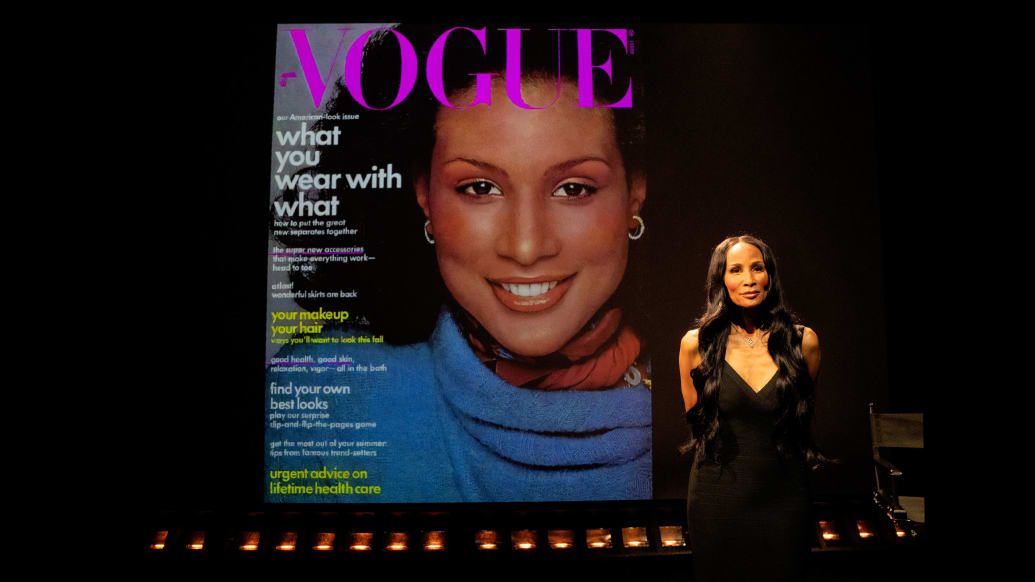 A photo of Beverly Johnson in front of a Vogue cover on which she is depicted