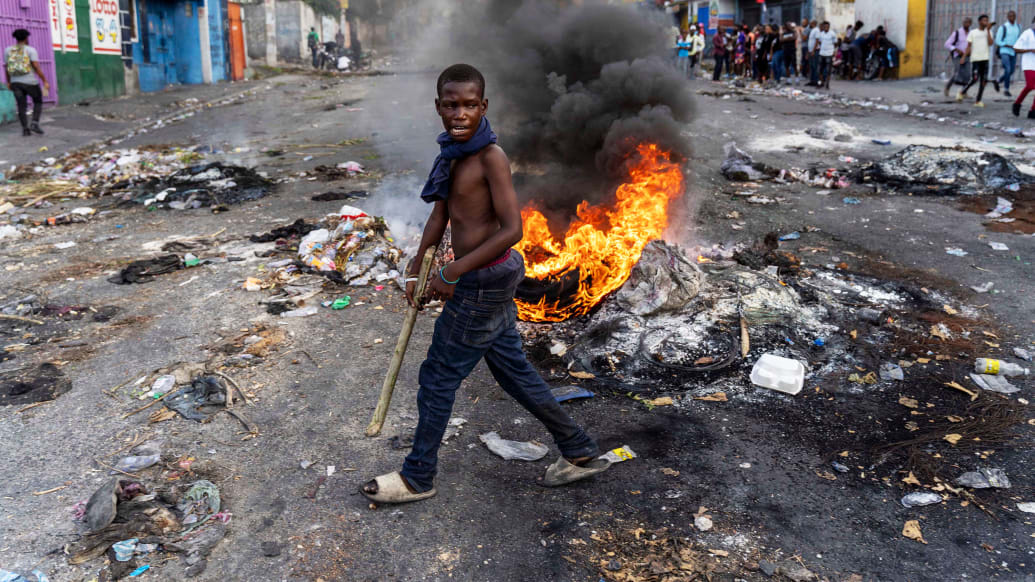 A mans walks past a burning barricade during a protest against Haitian Prime Minister Ariel Henry in Port-au-Prince last year.