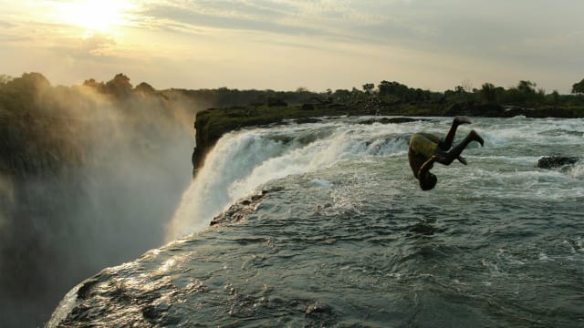 A Zambian man jumps into a pool on the edge of Victoria Falls