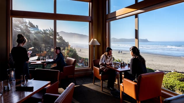 Guests sit in a restaurant at Long Beach Lodge overlooking the beach in Tofino, Canada.