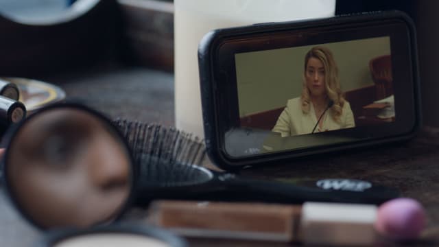 A still from Depp V Heard showing someone watching video of Amber Heard during her trial with Johnny Depp