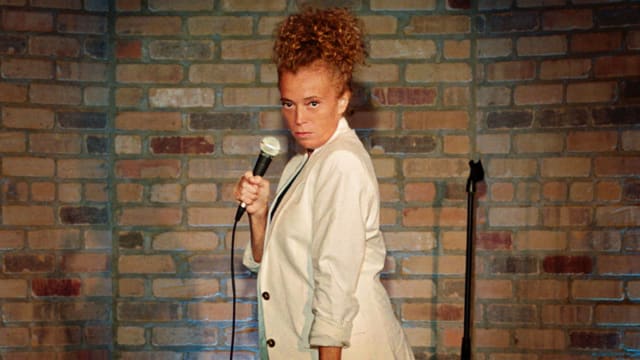 Michelle Wolf stands with a microphone on stage