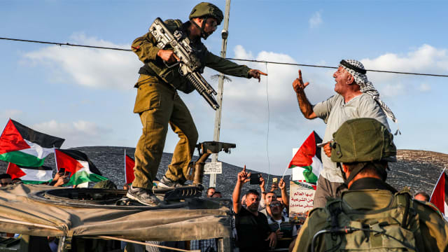 A photo of a Palestinian protester and an IDF soldier shouting at each other. 