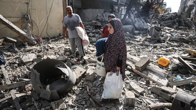A photo including Palestinians searching for their belongings among the rubble in Gaza City