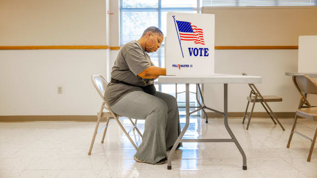 A woman seated at a polling station votes
