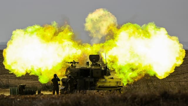 An IDF Artillery solider covers his ears as a shell is fired towards Gaza on October 11, 2023 near Netivot, Israel