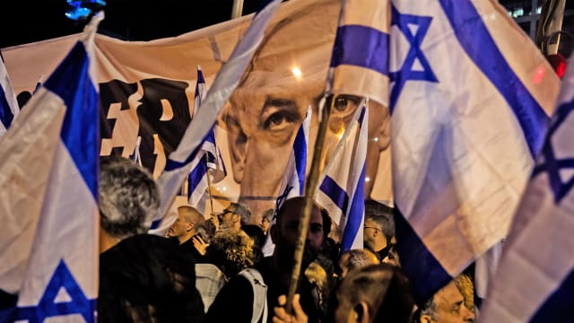 A photo of people waving Israeli flags with a picture of Benjamin Netanyahu poking out through the flags