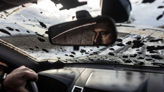 A Ukrainian soldier driving in Kupiansk can be seen in his rearview mirror